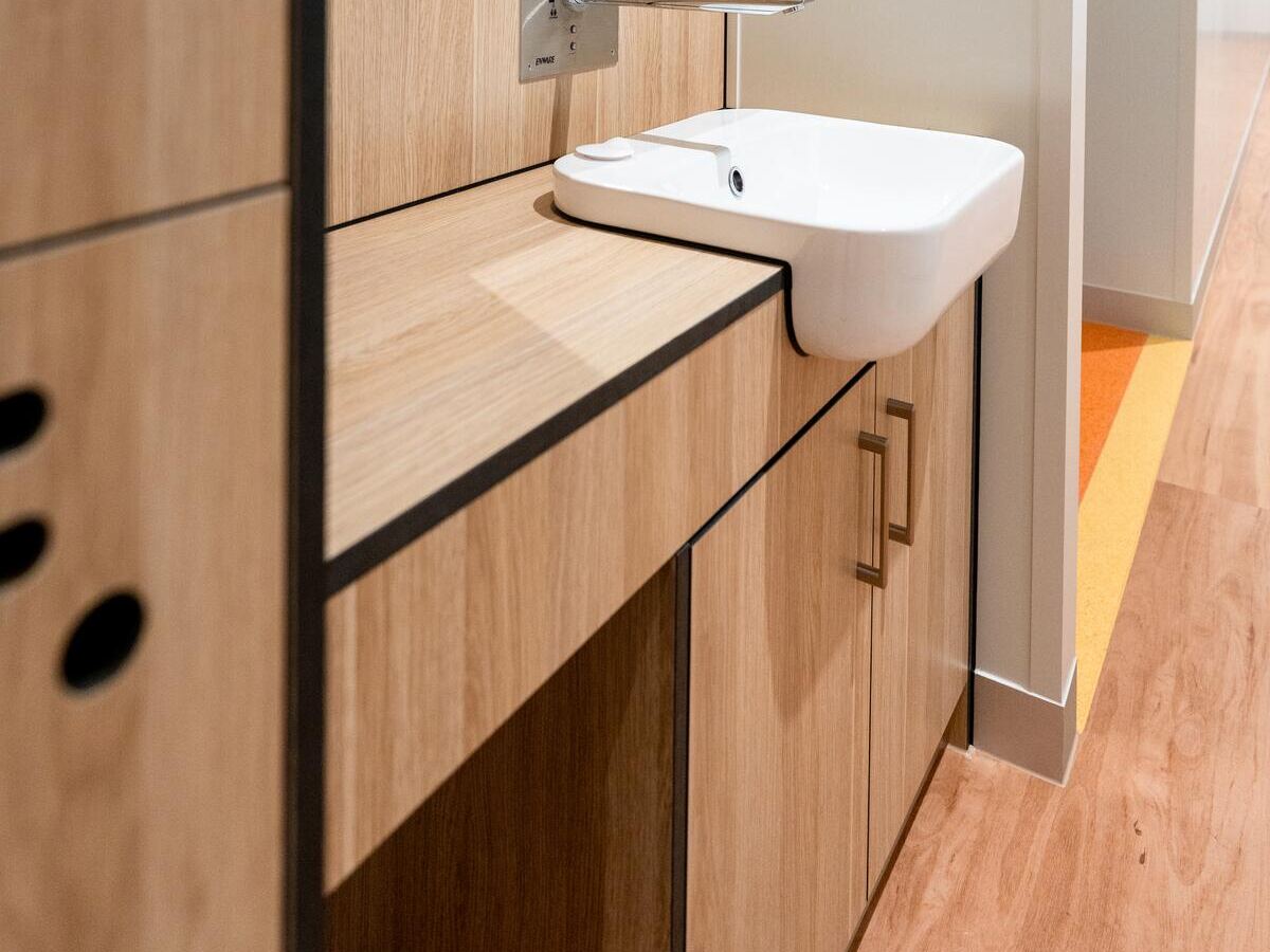 Timber plank flooring meeting coved vinyl beside a handwash station at PolyNovo, installed by JA Floors